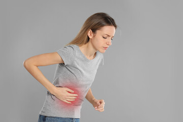 Young woman suffering from liver pain on grey background. Space for text