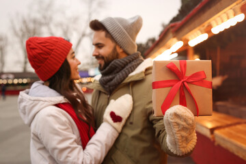 Lovely couple at winter fair, focus on Christmas present