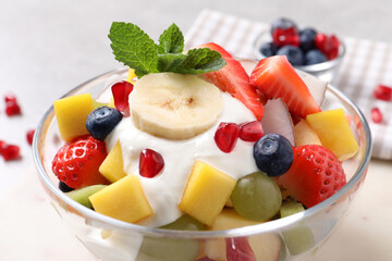 Delicious fruit salad with yogurt in bowl on table, closeup