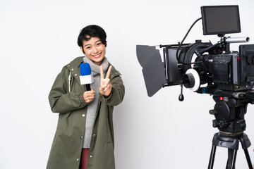 Reporter Vietnamese woman holding a microphone and reporting news smiling and showing victory sign