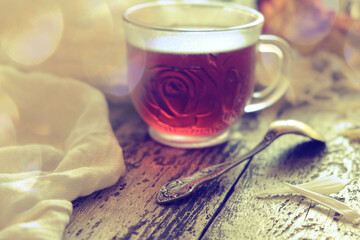 Cup of  tea, neutral scarf on wooden table, sun glare and bokeh, the concept of home comfort, retro atmosphere. Romantic morning
