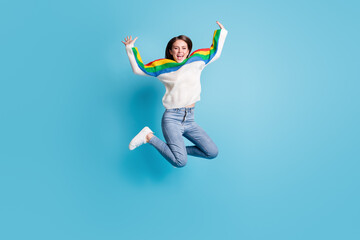 Full length photo of charming excited young lady wear colorful pullover jumping high rising arms isolated blue color background