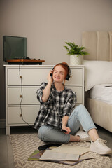 Young woman listening to music with turntable in bedroom