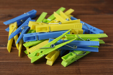 Pile of colorful plastic clothespins on wooden table, closeup