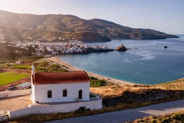 Elevated view to the town of Andros island, Cyclades, Greece, during sunset time with a traditional, Greek orthodox church in front
