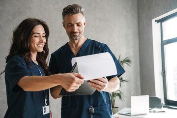 Two doctors in medical uniform looking at clipboard