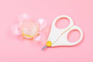 safe scissors and  soother  for babies on pastel pink background .