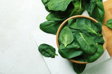 Bowl of spinach on board, on white textured table