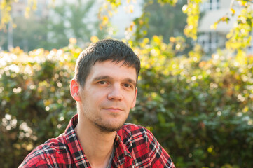 Portrait of a young man in a red shirt, autumn outside