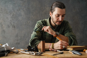 Middle aged man leathersmith working at his workshop