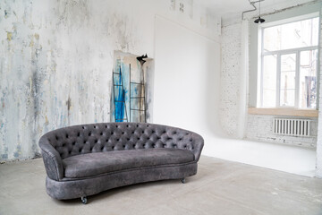 Loft interior. stylish grey sofa against gray wall with unusual colored plaster.