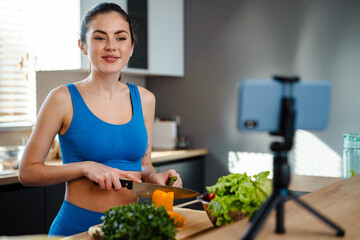 Obraz na płótnie Canvas Happy young healthy woman influencer preparing fresh salad