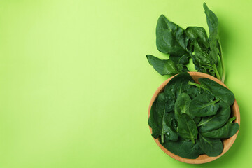 Bowl of spinach leaves on green background