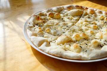 large freshly baked pizza with spices sprinkled with cheese in bright sunlight