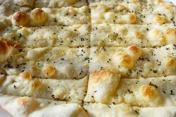 large freshly baked pizza with spices sprinkled with cheese in bright sunlight