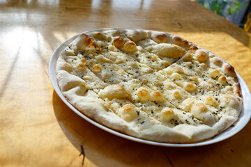 large freshly baked pizza with spices sprinkled with cheese in bright sunlight