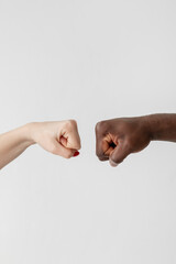 Multiethnic tolerance. Gender diversity. Racial cooperation. Discrimination problem. Conceptual art. White female and black male fists going to join together isolated light.