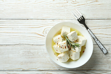 Bowl with feta cheese and fork on white wooden background