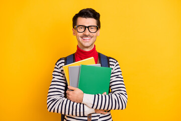 Portrait of satisfied person hands hold copybooks carry rucksack beaming smile isolated on yellow color background
