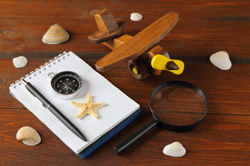 The still life from objects about ideas of travel, tourism, transportation and cost on the brown wooden background. The concepts of rest, travel, tourism, adventure and planning. 