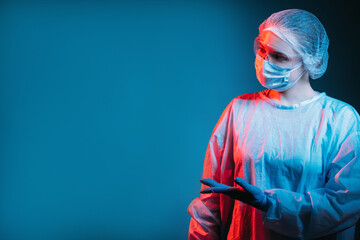 Covid-19 immunization. Pandemic banner. Laboratory research. Portrait of female doctor in ppe in red neon light offering invisible solution on copy space with open hand palm isolated on dark blue.