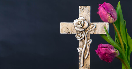 Ornate religious cross and fresh purple spring tulip flowers. Churches and funeral concept. Copy...