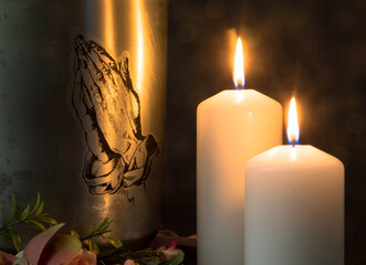 Mortuary urn with burning candles and flowers against dark background.Churches and funeral concept....