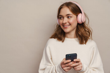 Young smiling woman listening music with headphones and cellphone