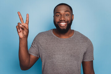 Photo of cheerful african man showing v-sign isolated blue background