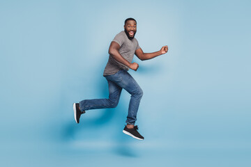 Full length view of afro guy jumping running isolated on blue background