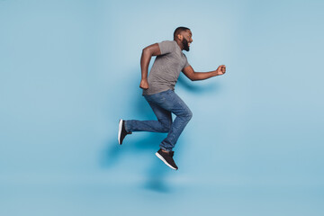Fototapeta na wymiar Full length view of afro guy jumping running isolated on blue background
