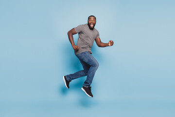 Full length view of afro guy jumping running isolated on blue background