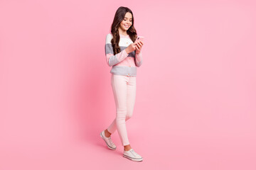 Full size profile side photo of young happy good mood girl blogger using smartphone isolated on pink color background