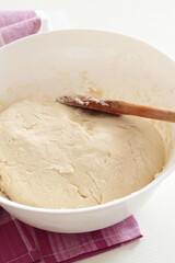 fresh dough in white bowl with wooden spoon