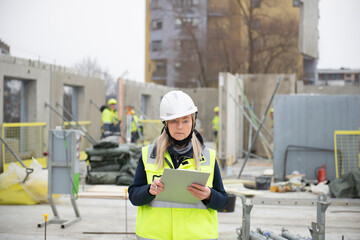 Woman construction site engineer architect worker with hard hat writes notes on the progress of work