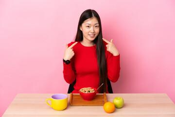 Young Chinese girl  having breakfast in a table giving a thumbs up gesture