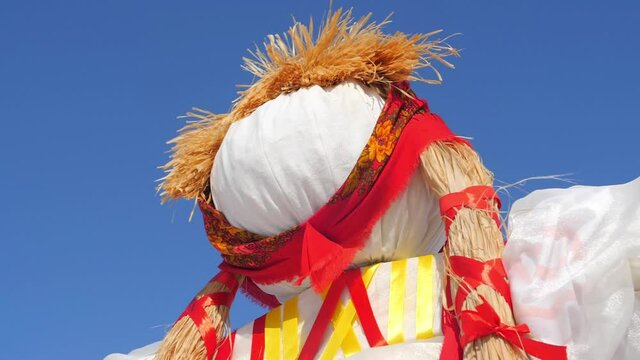 Slavic holiday Maslenitsa. Pagan doll against the blue sky. Quilted and bright pieces of fabric on the cook for future burning. Idol for the holiday. Pancake Festival. The wind blows the ribbons.