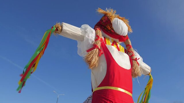 Slavic holiday Maslenitsa. Pagan doll against the blue sky. Quilted and bright pieces of fabric on the cook for future burning. Idol for the holiday. Pancake Festival. The wind blows the ribbons.