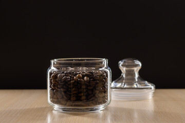 Grains of coffee in a glass jar on a black background.