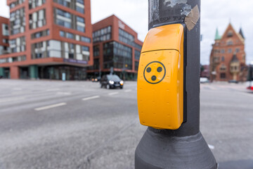 Anforderungskasten an einer Blindenampel mit Kreuzung im Hintergrund