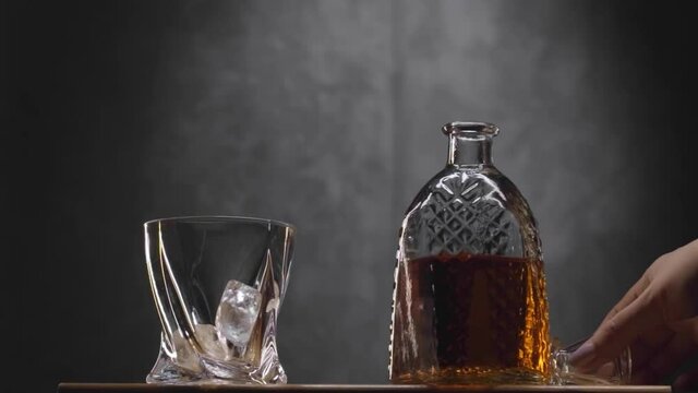 Whiskey glass and bottle on table against dark gray background