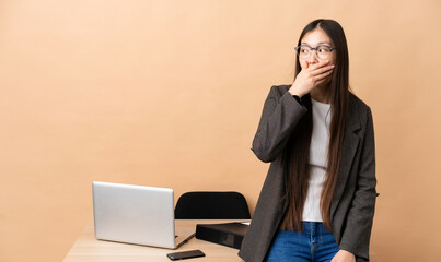 Chinese business woman in her workplace doing surprise gesture while looking to the side