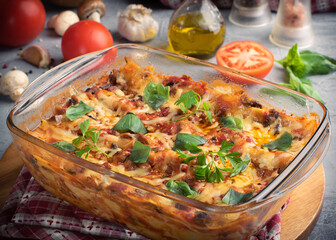 Tasty hot lasagna served with ingredients on gray background. Italian cuisine, menu, recipe. Homemade meat lasagna. Close up, side view.