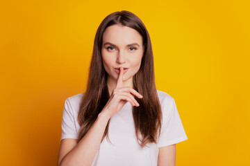 Photo of tender flirty lady finger close lips wear white t-shirt posing on yellow background