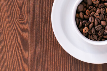 white cup, saucer and coffee beans on a wooden background