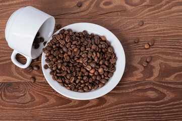 white cup and coffee beans on a saucer on a wooden background