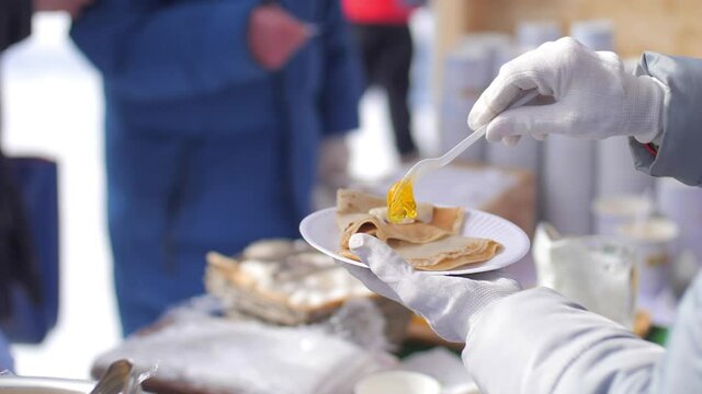 The cook puts a plate of crepe in the plastic on the street. Crepes with honey.