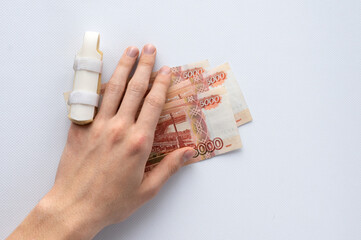 medical splint on a broken finger and money on a white background. Expensive medical services and insurance