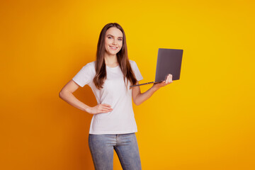 Photo of programmer lady hold netbook beaming smile wear white t-shirt posing on yellow background