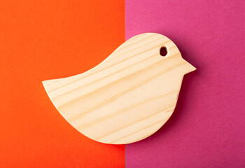 Figurine of a bird carved from solid pine by hand jigsaw. On a multi-colored background